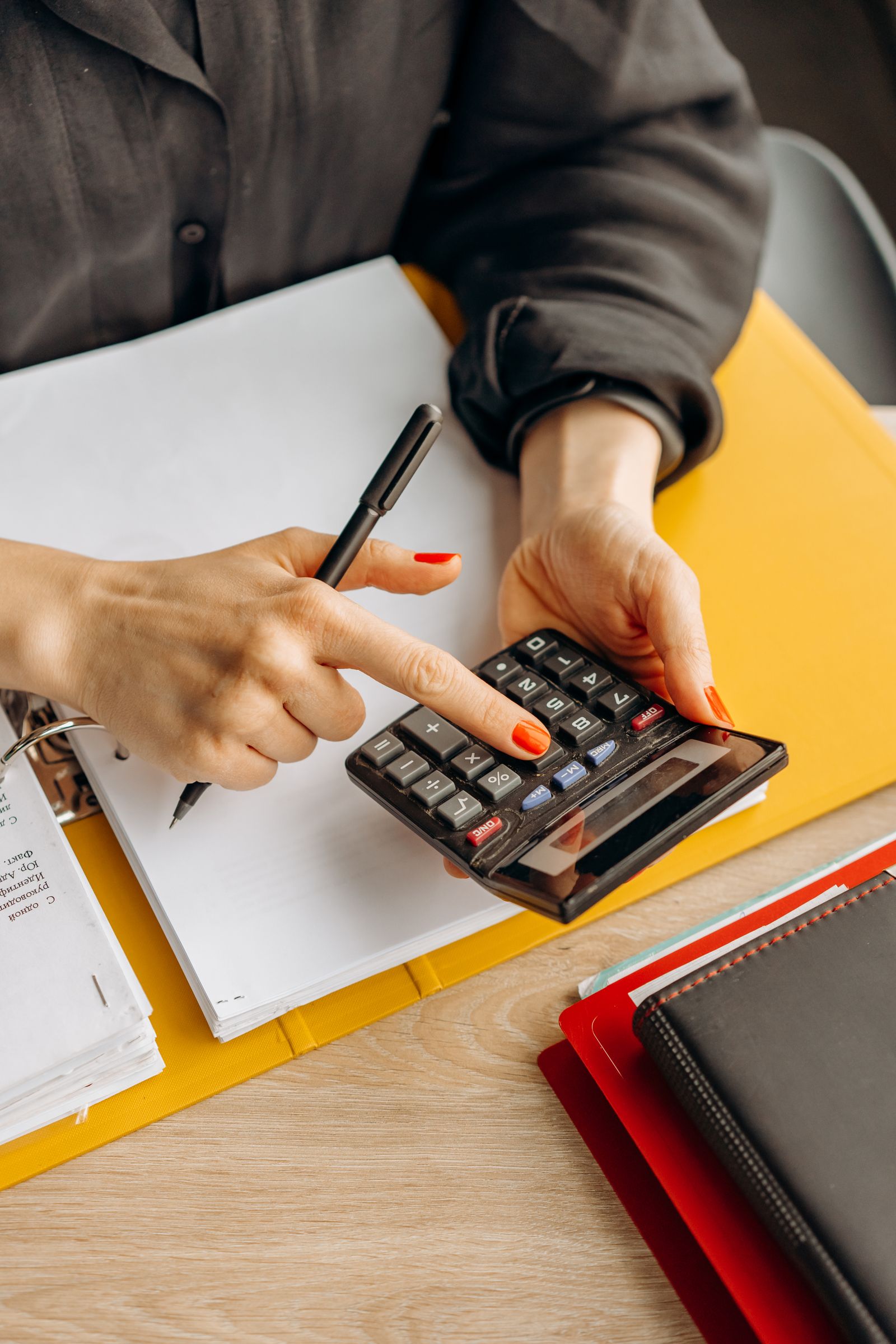 Hands working a calculator over an open ledger